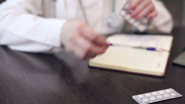 Doctor Working With Tablet Computer And Documents