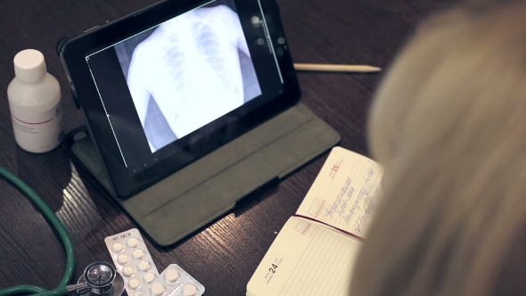 Doctor Working With Tablet Computer And Documents