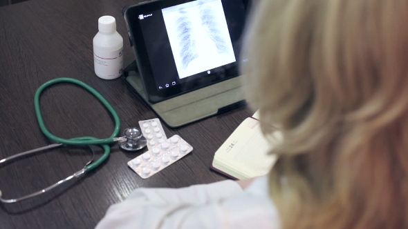 Doctor Working With Tablet Computer And Documents