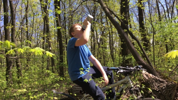 Boy On a Bicycle In The Woods Drinking Water 