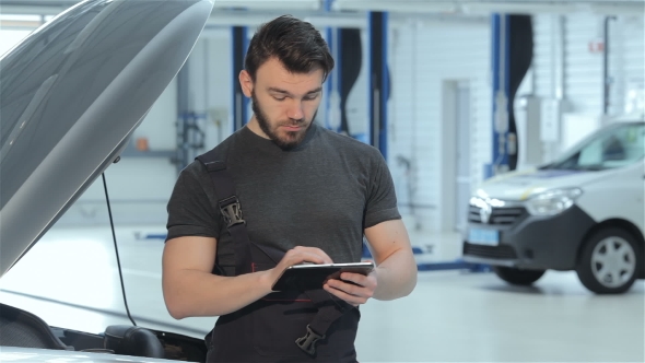 Mechanic Uses a Tablet At The Car Service alt