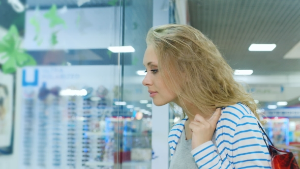 An Attractive Woman With Shopping Bags Dyal Looking In a Shop Window alt