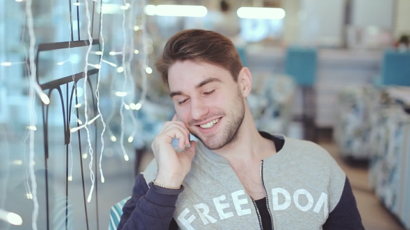 Happy Young Man Talking On Cell Phone And Smile In Cafe 
