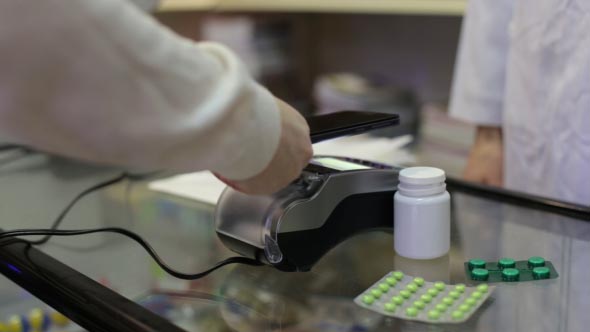 Woman Paying with a Phone at the Pharmacy alt