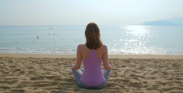 Young Woman Meditate on the Beach