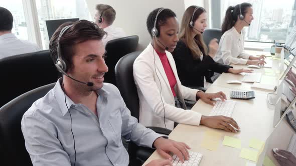 Multiethnic support team wearing headphones working in call center office