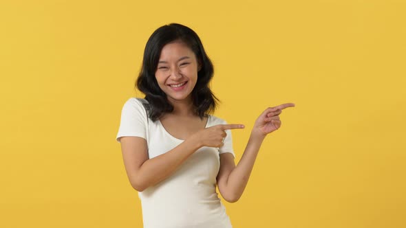 Young happy smiling Asian woman in white t-shirt opening hands and pointing left right