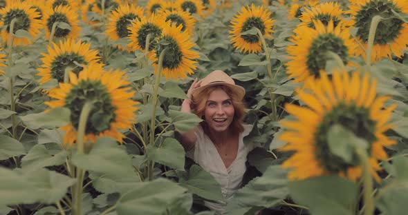 Happy Young Woman Walks in a Field with Sunflowers