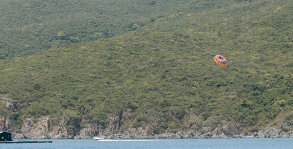 Tourists Sailing on Parachute above the Sea
