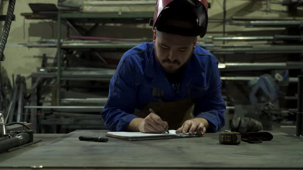 Concentrated mechanic in workshop writing notes in notepad alt