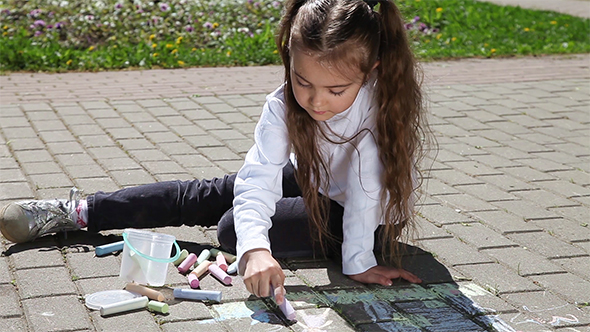 Little Girl Draws With Chalks 