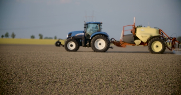 Tractor Spray Fertilize On Field With Chemicals In Agriculture Field. alt