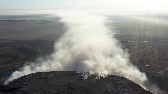 Aerial view of smoke from burning garbage pile in landfill, Earth pollution concept alt