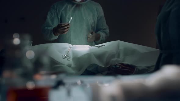 Professional Surgeon Making Incision Before Operating in Dark Surgery Room alt