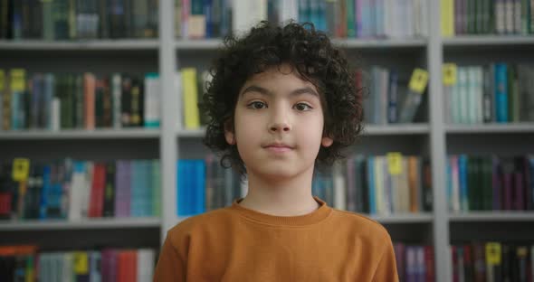 Little Biracial Boy with Kinky Hair Stands in School Library