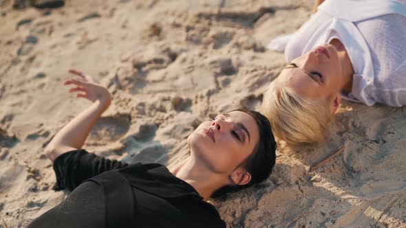 Girls Meditate Lying on the Sand
