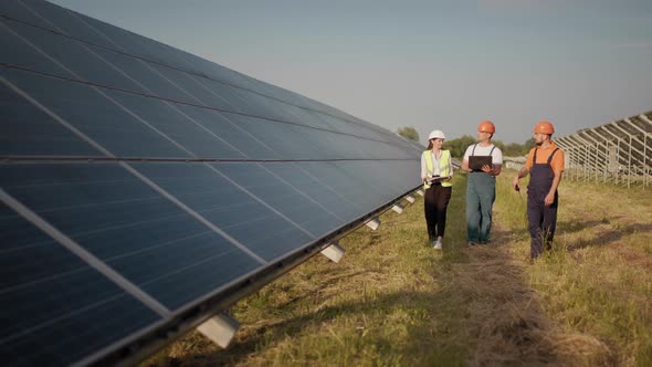 Business Team of Industrial Engineers Walking on Solar Farm and Discussing alt