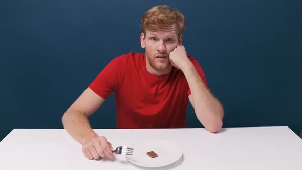 Funny Hungry Man Eats a Small Piece of Chocolate From a Halfempty Plate alt