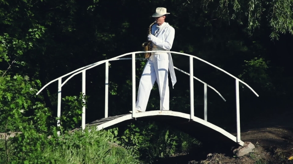 Saxophonist In a White Frock Coat And Hat Playing On The Bridge.
