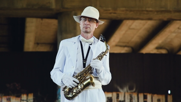 Saxophonist In a White Hat And White Coat With a Saxophone In His Hands. 