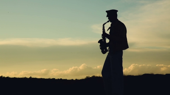 Saxophonist. Man Playing On Saxophone Against The Background Of Sunset
