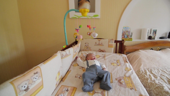 Little Cute Baby Boy Lying In Crib With Toy alt