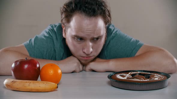 Man Is Choosing Between Cake and Fruits alt
