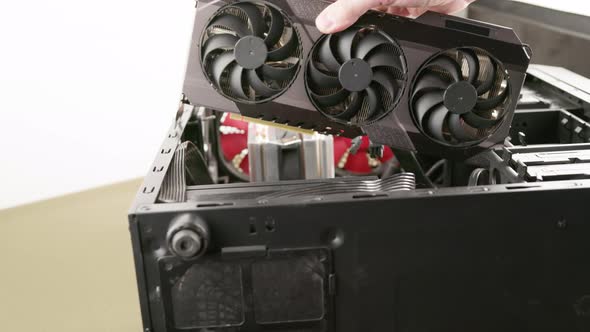 Caucasian Hand Trying to Fit a New Big Black Triple Fan Graphics Card Into Black Pc Case Card Does