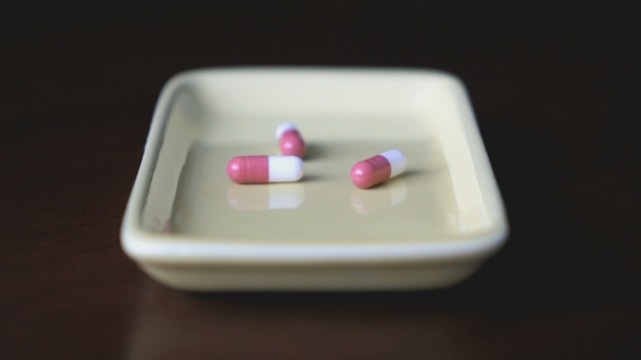 Pills Are Scattered In The Container On The Table
