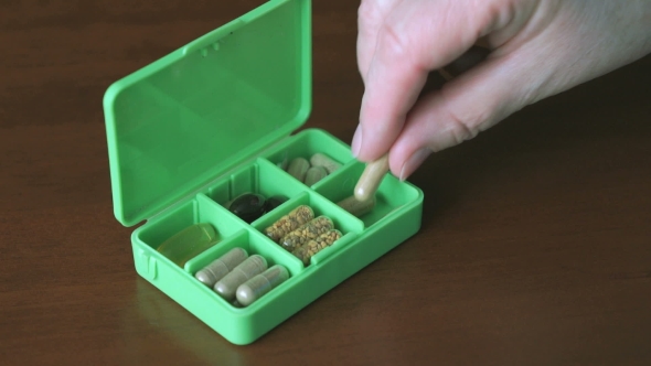 Woman's Hand Puts Capsules Tablets In Container