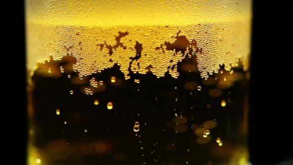 Beer Is Pouring Into The Glass. Bubbles.