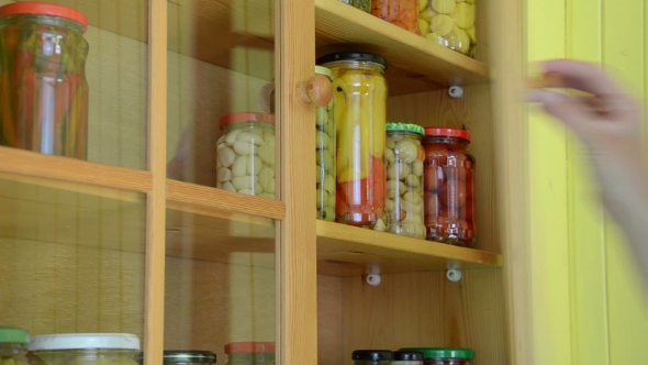 Woman Hand Take Canned Glass Pot Of Peppers From Food Shelf