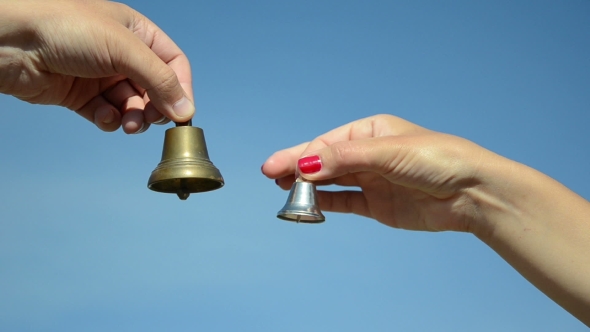 Boy And Girl Hands Jingle With Silver Bronze Bell On Blue Sky