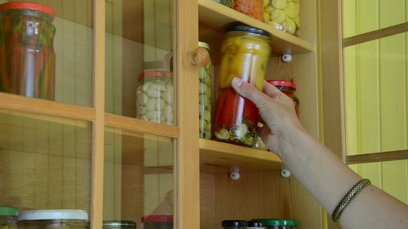 Girl Hand Put Canned Glass Pot Of Peppers To Food Storage Shelf