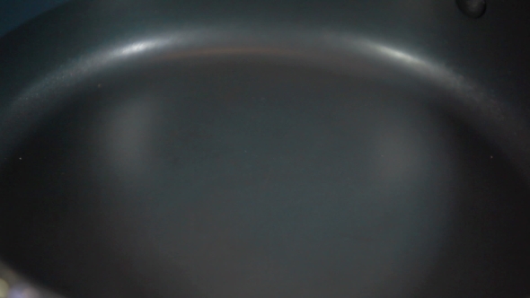 Egg Being Dropped In And Frying On Hot Iron Grill