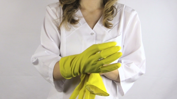 Woman In White Robe Smock Put On Yellow Rubber Gloves On Hands