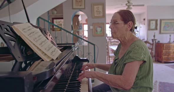Old woman playing a grand piano at her home alt