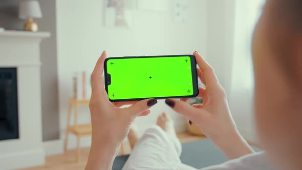 Young Female Using Smart Phone Sitting On Sofa At Home.