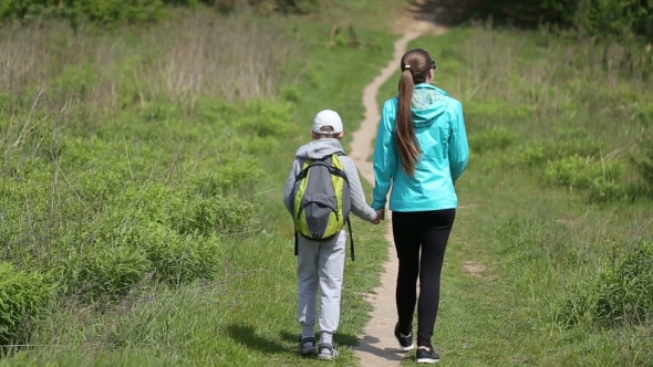 Mother And Son Are On The Track, Seen From Behind In Battle Dress. a Walk In The Fresh Air.