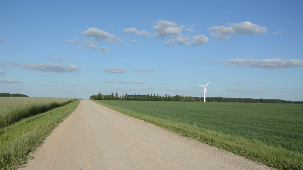 Rural Gravel Road Between Fields And Wind Mill Windmill Rotate