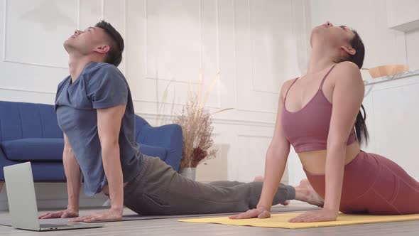 Asian couple practicing yoga together at home