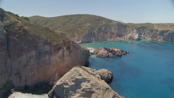 Flying Over Cliffs Cascading into the Aegean Sea and Towards Small Bay in Milos alt