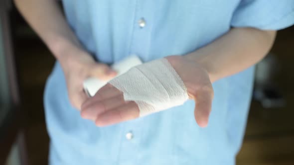 A woman has difficulty in bandaging her injured arm, she is very uncomfortable alt