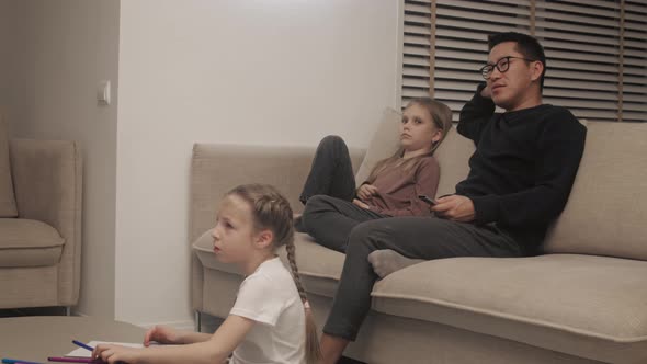 Father watching TV with daughters