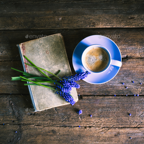 Blue flowers and a cup of coffee with a book on a wooden background Stock Photo by ollinka