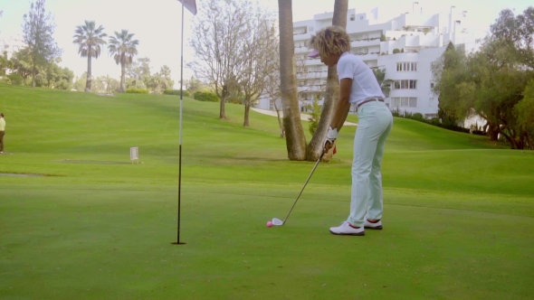 Young Woman Putting For The Hole On a Golf Course alt