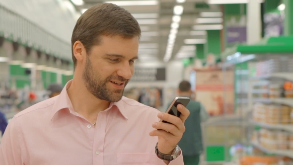 Cheerful Man Using Mobile Phone In Store