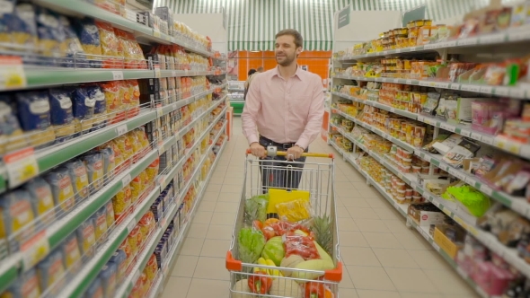 Smiling Man Pushing Trolley And Buy Food At Supermatket