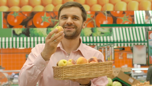 Smiling Man In Supermarket Holding Wicker Basket With Apricots