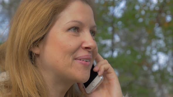 Pretty blond girl outdoor enjoying flirting on phone 4K 2160p UHD video - Modern woman phone talking alt